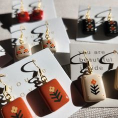 four pairs of earrings with designs on them sitting on top of a piece of paper