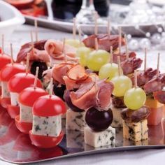 an assortment of appetizers are arranged on a platter with grapes and meats