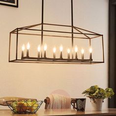 a chandelier hanging over a dining room table filled with fruit and candles on it