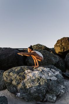 a man standing on top of a rock next to a pile of rocks and holding a surfboard