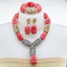 a necklace, bracelet and earring set with roses on the front is shown in red