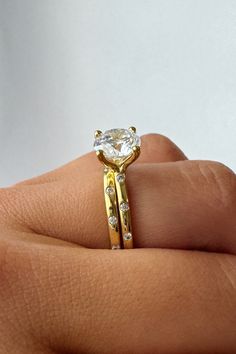 a woman's hand holding a yellow gold ring with a white diamond in it