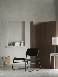 a black chair sitting on top of a white floor next to a table and lamp