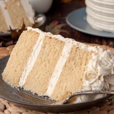 a slice of cake with white frosting on a plate next to plates and forks