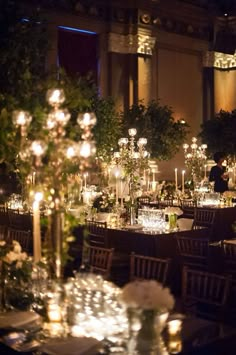 the tables are set with candles and centerpieces for an elegant wedding reception at night