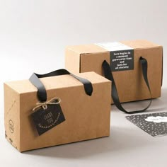 two brown boxes with black ribbons and tags on them, one has a tag attached to it