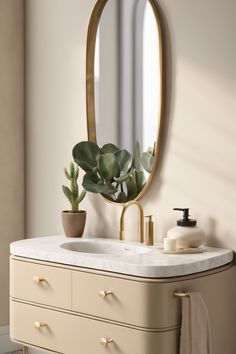 Elegant bathroom vanity with an oval mirror, potted plant, and soap dispenser on a marble countertop.