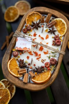 orange slices, cinnamons and spices are arranged in a wooden tray on a table