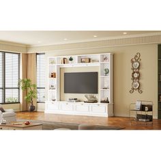 a living room filled with furniture and a flat screen tv on top of a white entertainment center