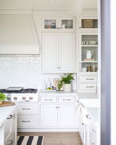 a kitchen with white cabinets and black and white rug