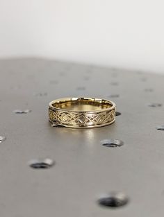 a gold ring sitting on top of a metal surface with drops of water around it