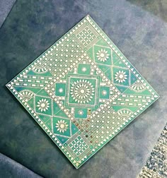 a green and white tile on the ground with an intricate design in it's center