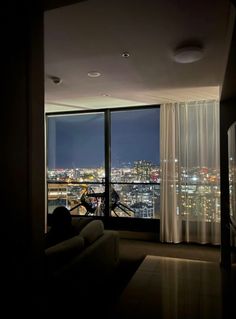 a living room filled with furniture and a large window overlooking the city lights at night