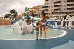 a woman and child standing in front of a water park