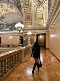 a woman is walking down the stairs in an ornate building