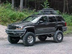 a jeep parked on the side of a road in front of some trees and bushes