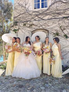 a group of women standing next to each other in front of a building holding umbrellas