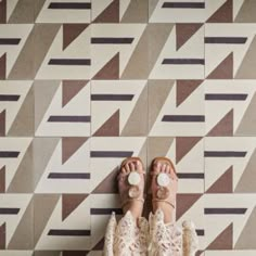 a person standing on top of a tiled floor with their feet up in the air