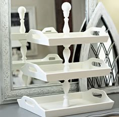 three white trays are stacked on top of each other in front of a mirror