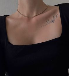 a woman with a tattoo on her chest wearing a black shirt and gold chain necklace