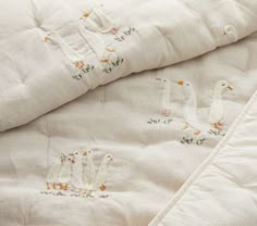 two white quilted bedspreads with ducks and flowers on them, next to each other