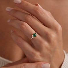 a woman's hand with an emerald and diamond ring