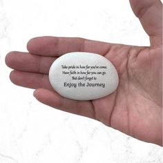 a hand holding a white stone with a poem on it