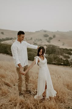 a man and woman holding hands in a field