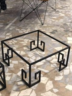 an unusual coffee table made out of black metal with geometric shapes on the top and bottom