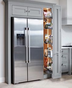 a stainless steel refrigerator with its doors open in a kitchen area next to an island