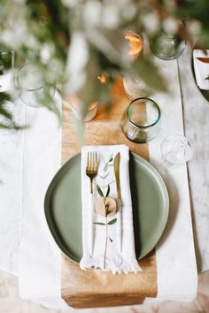 the place setting is ready to be served at this elegant wedding reception with greenery and white linen napkins