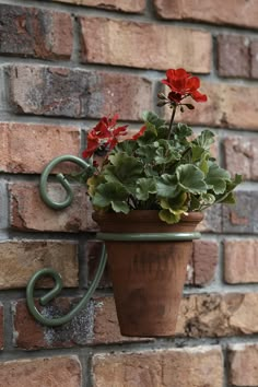 a potted plant is hanging on a brick wall with an iron hook attached to it