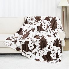 a white couch with a brown and white cow print blanket on it's back