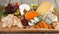 an assortment of cheeses and crackers on a cutting board