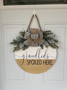 a wooden sign that says grandadds spoiled here hanging on the front door with a bow