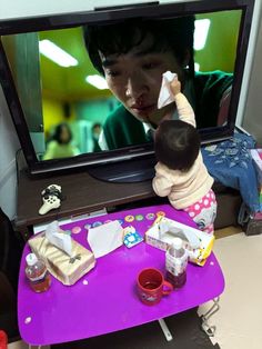 a young child is playing on the television screen with his mother and baby in front of him