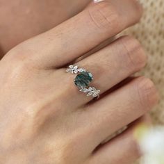 a woman's hand with a ring on her finger and an emerald stone in the middle