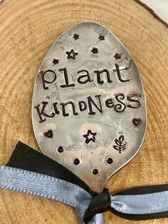 a spoon with the words plant kindness on it sitting on top of a piece of wood