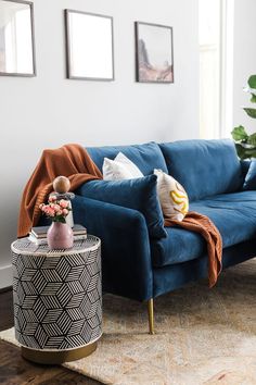 a living room with a blue couch and some pictures on the wall next to it