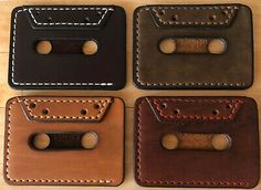 four leather wallets with holes in them on top of a wooden table next to each other