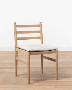 a wooden chair sitting on top of a hard wood floor next to a white wall