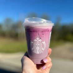 a hand holding up a purple starbucks drink