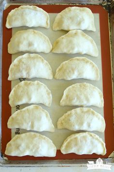 six uncooked dumplings on a baking sheet ready to go into the oven