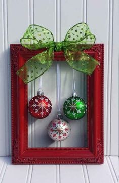 a red frame with christmas ornaments hanging from it's sides and a green bow on top