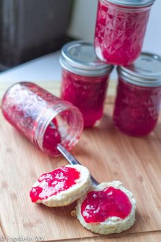 jam being spread on top of biscuits with a jar in the back ground next to it