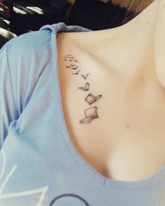 a woman with a tattoo on her neck and some birds flying in the sky behind her