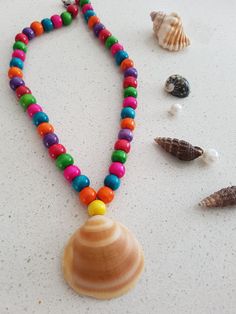 there is a necklace made out of colorful beads and seashells on the table