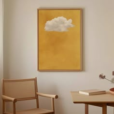 a painting hangs on the wall next to two chairs and a table with a potted plant