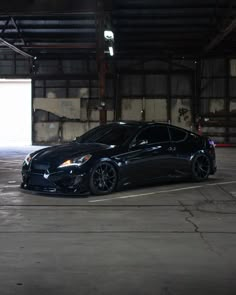 a black sports car parked in an empty parking lot with no one around it at night