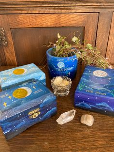 three blue boxes sitting on top of a wooden table next to a potted plant